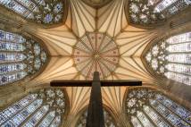 View upwards of wooden cross with branching roof of the Minster in view