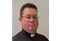 Head and shoulders of man around 50 years old dressed in black clerical shirt and wearing glasses
