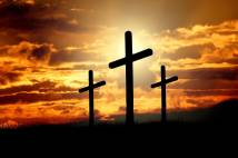 silhouettes of 3 crosses with setting sun behind