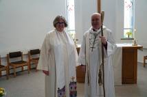A woman and a man standing inside a church dressed in white clerical robes