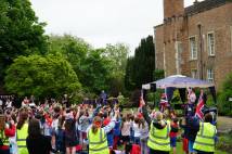 Staff and pupils waving flags together in grounds of large building