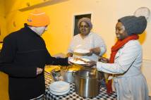 Two ladies serving a man a plate of food