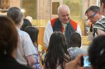 Inside a church - robed clergyman with children gathered around him