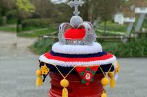 A post box with knitted crown on top of it