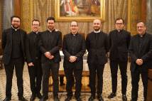 7 men dressed in black clerical clothes standing inside a church building