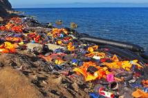 Discarded lifejackets on a beach with upturned small boat