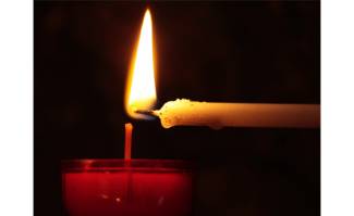 A red candle being lit from a thin white candle - dark background