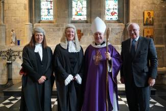 2 women dressed in lawyers wig and gown next to Bishop in purple robes and white mitre