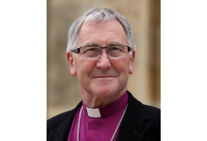 Head and shoulders of Bishop Glyn dressed in black suit jacket and purple shirt with dog collar