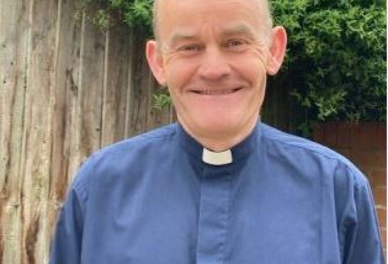 Head and shoulders of man in blue clergy shirt and dog collar