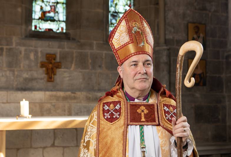Archbishop in red and gold robes holding staff in his hand