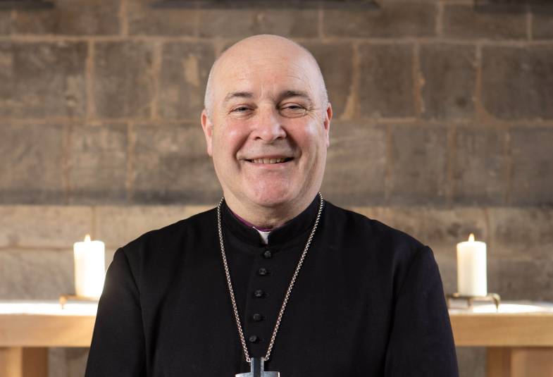 Archbishop Stephen is stood in a chapel and smiling at the camera