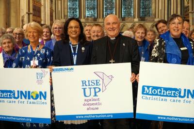 Archbishop Stephen stands with members of the Mothers Union, holding up RISE UP against domestic abuse posters