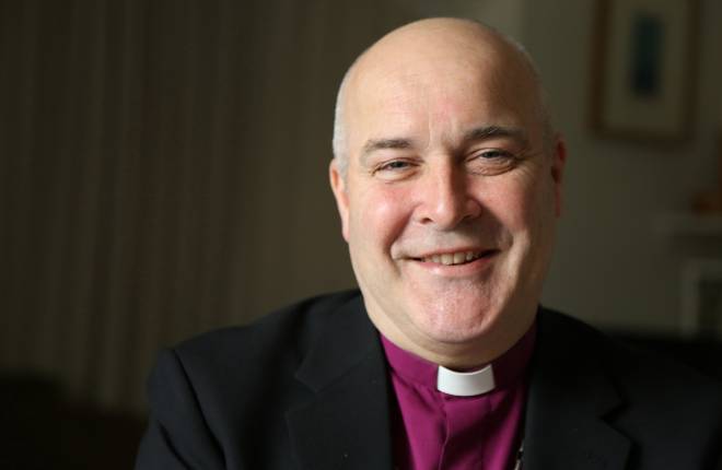 Head and shoulders of Archbishop dressed in purple clerical shirt and black suit