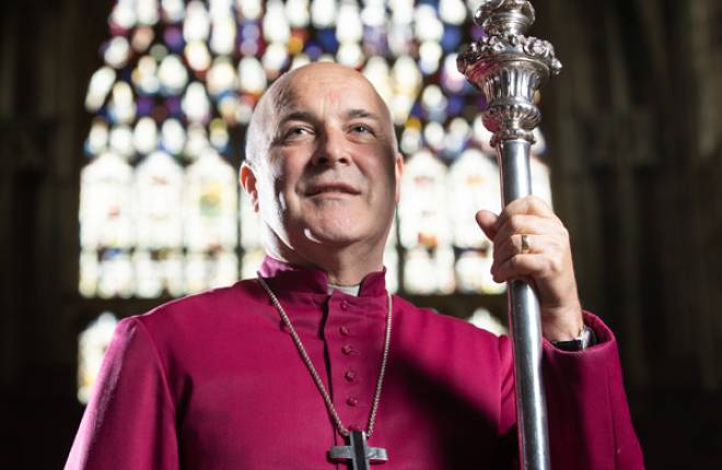 Archbishop head and shoulders purple cassock with crozier, Minster window behind