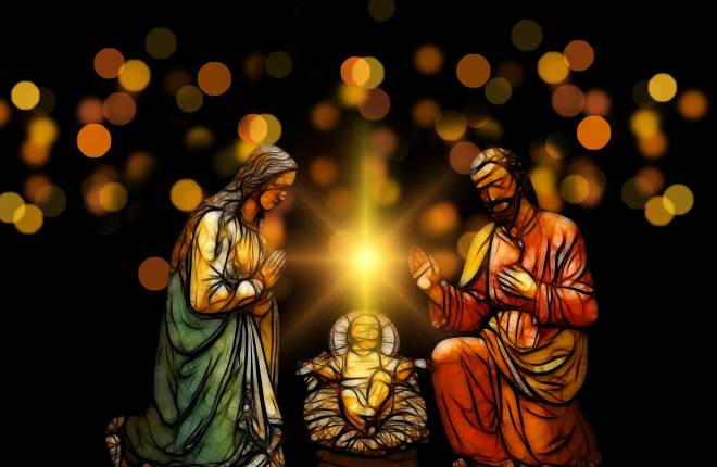 Figurines of Mary Joseph and baby Jesus in a manger with a bright light shining above the manger