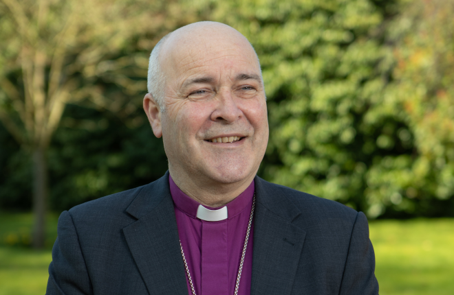 Archbishop of York, Stephen Cottrell, looks off camera with trees in the background