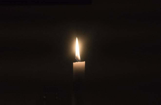 One candle burning in darkness